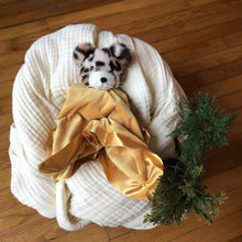 Load image into Gallery viewer, Gold plushie blanket with a leopard head , cradled on white muslin blanket . Wooden background with greenery. 