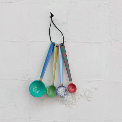 Set of 4 colorful measuring spoons hanging on a white background.