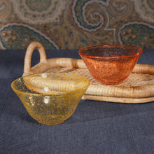 Load image into Gallery viewer, Two glass bowls, one gold and one orange , on a woven tray with a paisley background and blue surface.