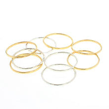 Load image into Gallery viewer, Set of 14K gold-filled and sterling silver stacking rings with a soft hammered finish, arranged in a loose cluster on a white background. 