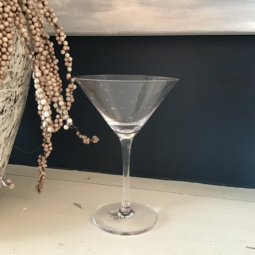 Clear martini glass on a white surface with a dark background