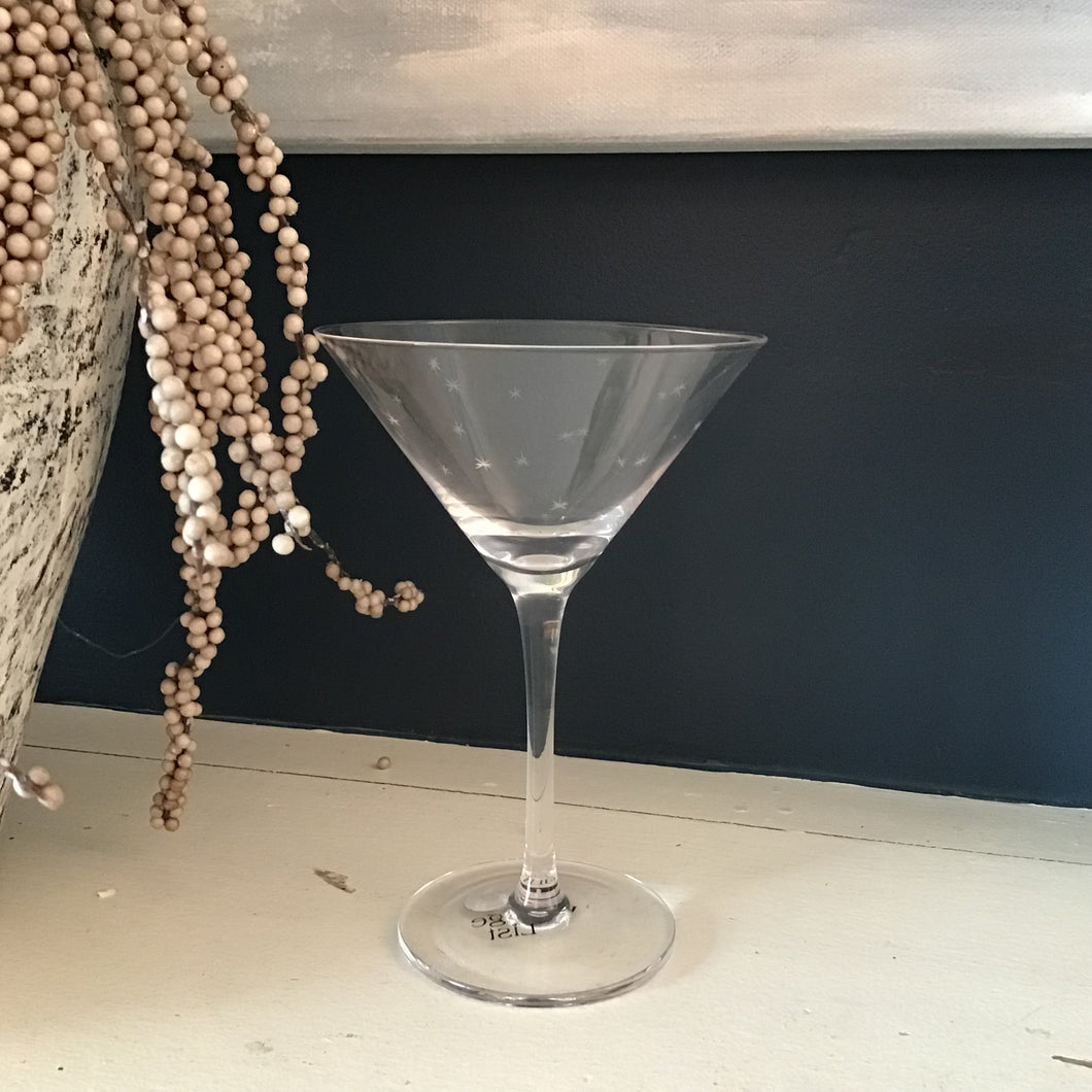 Clear martini glass on a white surface with a dark background