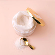 Load image into Gallery viewer, Open jar of Snowdrop bath salts with a gold lid resting to the side and a small gold spoon filled with salts on a soft pink background.