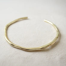 Load image into Gallery viewer, Close-up of a 14K gold double semi-matte plated brass choker necklace featuring a gently uneven, organic shape displayed on a cream woven fabric surface.  