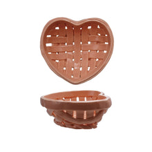 Load image into Gallery viewer, A pink heart shaped ceramic basket with a woven design upright against white background  so can see the inside , and another sitting flush on a white background. 