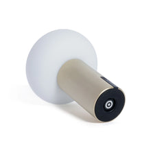 Load image into Gallery viewer, Bottom view of a rechargeable table light with a textured gold cylindrical base and a frosted oval shade, showing the circular black charging interface on the underside, displayed against a white background.   