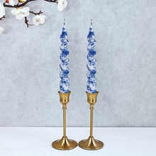 Load image into Gallery viewer, Two blue-and-white floral twisted taper candles in gold candlesticks on a white surface.  