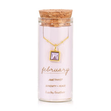 Load image into Gallery viewer, February birthstone necklace featuring a square light-purple amethyst glass crystal pendant in 14K gold-dipped metal, displayed inside a clear glass bottle with a cork lid and a label card reading "February  - Amethyst - Serenity + Peace," displayed on a white background. 