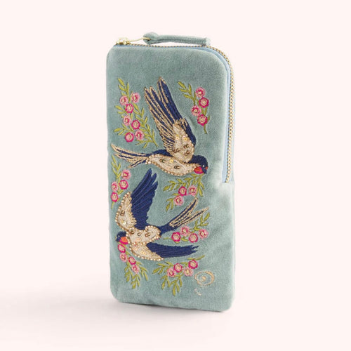 Light blue velvet zippered sunglass pouch with embroidered blue and white swallows and pink floral design. Against a white background.