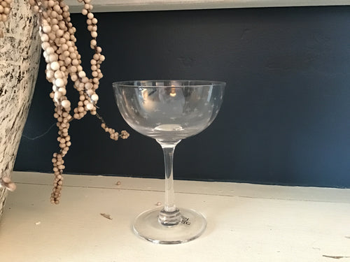 Clear glass coupe with a dark blue wall in the background