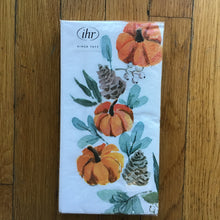 Load image into Gallery viewer, Pack of white paper napkins with orange pumpkins, brown pinecones, white berries, and green leaves. Napkins are wrapped in plastic packaging with a white label on the upper left corner. &quot;ihr&quot; and &quot;SINCE 1977&quot; in black print on the white label. Napkins are lying on a brown wooden plank surface.
