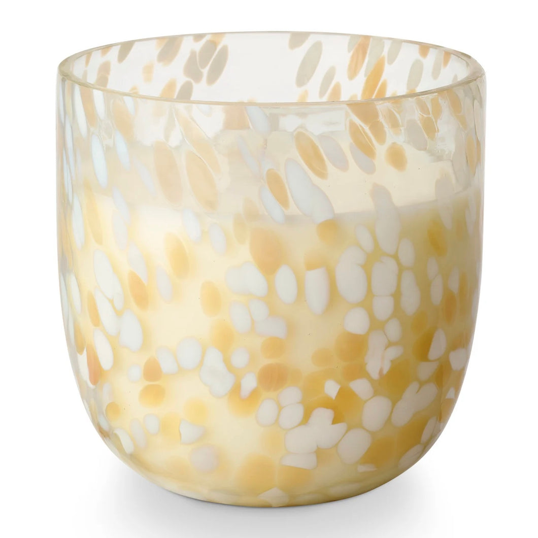 A white soy candle in a glass jar with a beige and white confetti pattern on a white background.