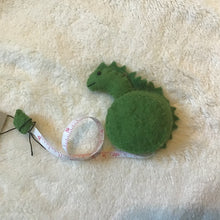 Load image into Gallery viewer, Green felt dinosaur measuring tape, lying on beige carpet. 