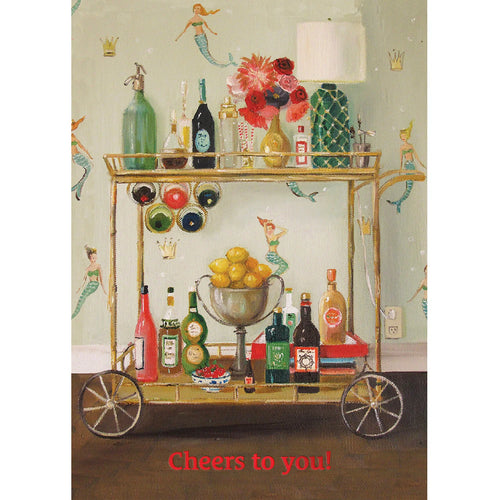 Greeting card depicting a gold vintage bar cart with with various multi-colored liquor bottles, a bouquet of pink flowers, a pedestal bowl filled with lemons, and a green lamp on it. The cart is sitting in a room with brown hardwood floors and wallpaper with a mermaid and crown print. The bottom of the card reads 