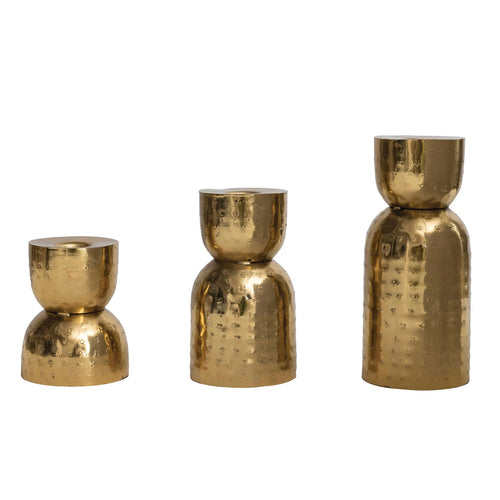 Three gold metallic candle holders of varying sizes on a white background