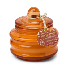 Load image into Gallery viewer, A glass candle in the color pumpkin with a visible tag on a white background. Body of glass is ribbed. The tag has &quot;PUMPKIN SPICE&quot;, &quot;notes of apple &amp; vanilla&quot;, and &quot;Soy Wax Candle&quot; text. 