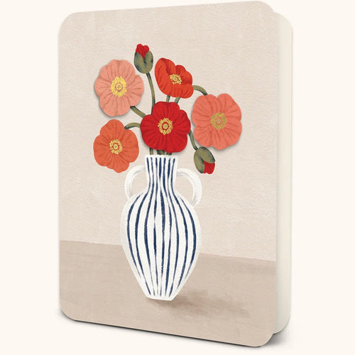 Greeting card featuring an illustration of a white vase with navy vertical stripes filled with red, coral, and pink poppy flowers. Displayed against a white background.  