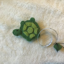 Load image into Gallery viewer, Green felt turtle measuring tape  on a beige carpet.
