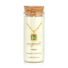 Load image into Gallery viewer, August birthstone necklace featuring a square light-green peridot glass crystal pendant framed in 14K gold-dipped metal, displayed inside a clear glass bottle with a cork lid and a label card reading "August - Peridot - Curiosity + Strength," displayed against a white background. 