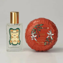 Load image into Gallery viewer, Granado Oud travel-size cologne bottle with gold cap and decorative floral label beside round orange floral-wrapped Oud bar soap against white background. 