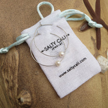 Load image into Gallery viewer, Silver hoop earrings with pearls on a Salty Cali Jewelry pouch against a sandy beach background.