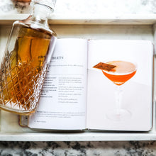 Load image into Gallery viewer, Open "Rosé Cocktails" recipe book with cocktail photo and recipe with a glass decanter on a white tray.