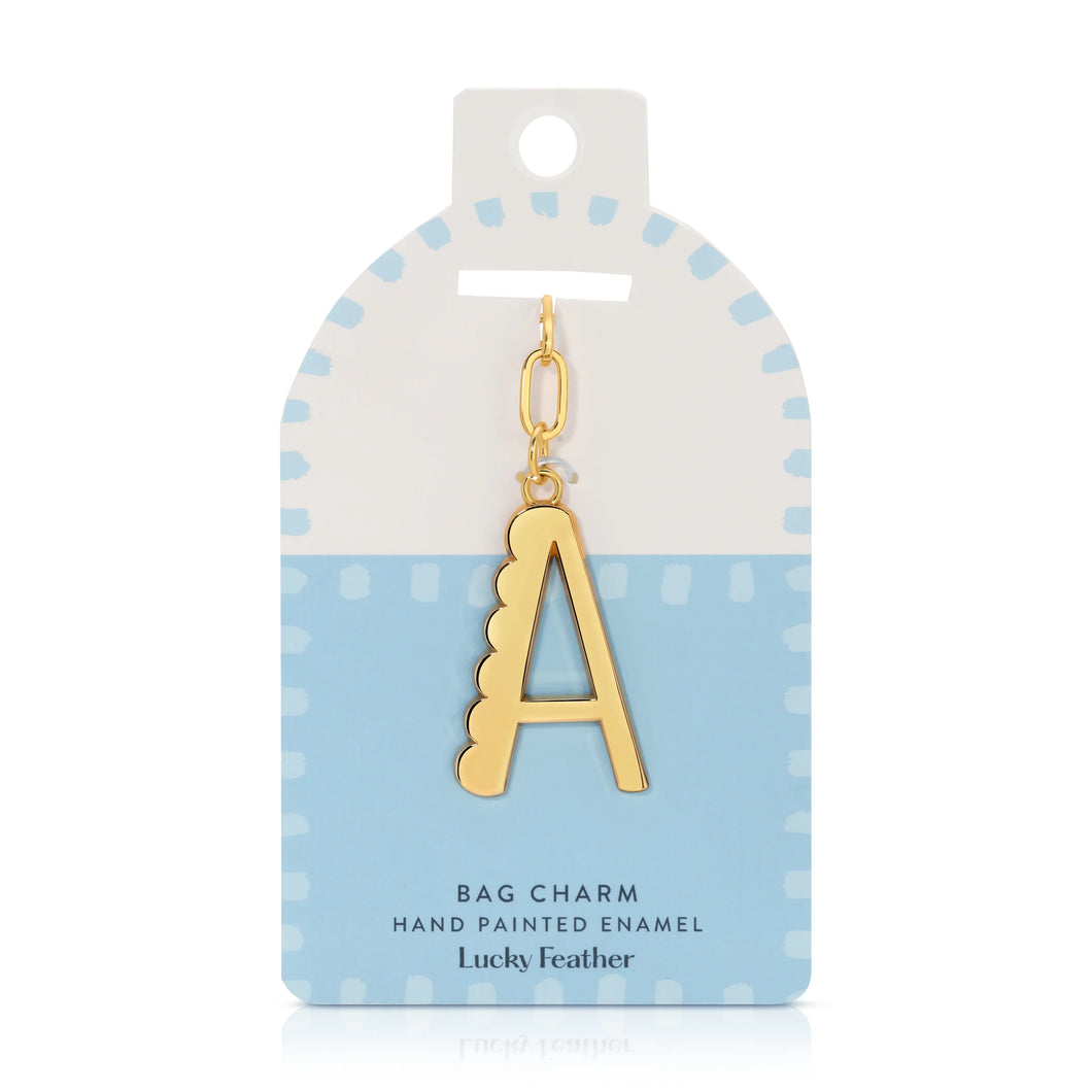 14K gold-plated hand-painted enamel initial bag charm featuring the letter A with a scalloped edge design and a brushed gold finish, attached to a key ring and clasp. Displayed on a white and light blue Lucky Feather card featuring light blue dotted brush-stroke borders and labeled 