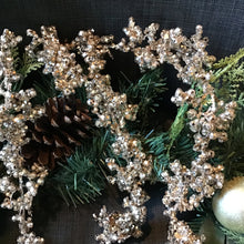 Load image into Gallery viewer, Glitter garland with shimmering champagne beads intertwined with pine greenery, pinecones, and a ball ornament against a dark gray background.  
