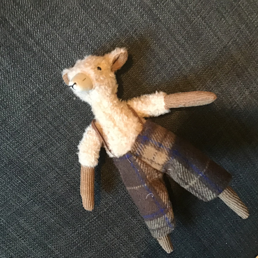 Stuffed toy fox wearing a plaid scarf on a dark textured surface