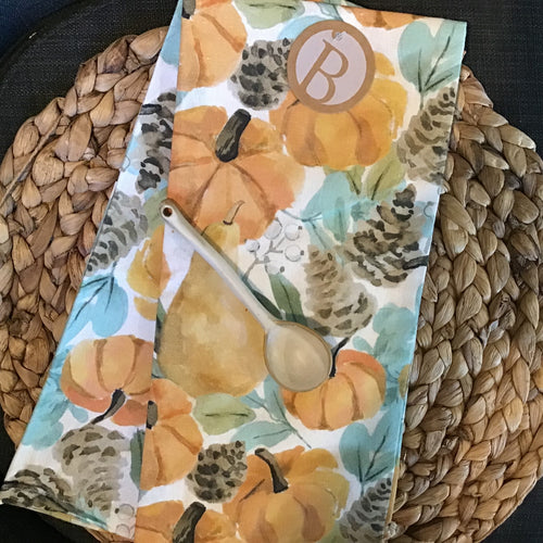 Folded cotton tea towel with a harvest theme and a brown round tag with 