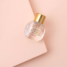 Load image into Gallery viewer, Mini Snowdrop eau de parfum in a clear glass bottle with a gold cap, styled on a powder pink background. 