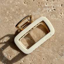 Load image into Gallery viewer, White rectangular metal claw clip with gold hardware displayed on a beige travertine surface with soft shadows.