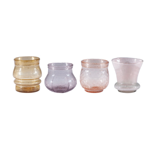Set of four glass candle holders in different colors on a white background