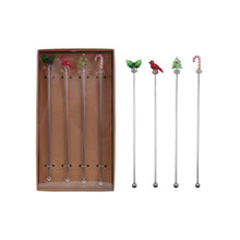Load image into Gallery viewer, Set of four glass holiday drink stirrers with festive toppers-holly leaves, a red cardinal, a candy cane, and a Christmas tree-displayed in a brown packaging box and on a white background. 