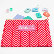 Load image into Gallery viewer, Red and pink chevron-patterned Mahjong accessory bag with a gold zipper and a pink rectangular patch with "MAHJ" on it, displayed with colorful Mahjong tiles, dice, and score card on a white surface.