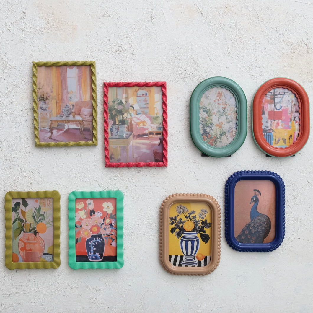 Set of eight colorful picture frames with various designs. Each frame has a different picture inside .  Hanging on a textured , white wall.