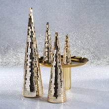 Load image into Gallery viewer, Collection of four gold prism cone decor trees with two large trees in the front and two smaller trees on a gold pedestal tray in the background, displayed on a shimmering silver surface and background.