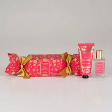 Load image into Gallery viewer, Granado Flora Magnifica scented cracker with bright pink packaging and gold botanical design and gold ribbon bows beside Floral Magnifica perfume in a clear glass bottle with gold cap and hand cream in a pink tube with black cap on a white background. 