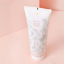 Load image into Gallery viewer, Back view of Lollia Snowdrop body gel in a powder blue botanical-print tube, displayed on a powder pink background. 