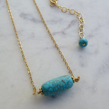 Load image into Gallery viewer, Necklace with a large turquoise bead on gold chain laying on a marble surface