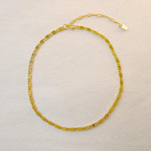 Load image into Gallery viewer, Ion-plated gold-plated brass casted bar chain necklace with reflective, light-catching links and an extended open-link chain, displayed on a soft white textured background. 