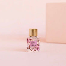 Load image into Gallery viewer, Small floral bottle of Lollia No 19 perfume with a gold cap on a pink background