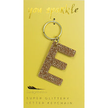 Load image into Gallery viewer, Gold glittery letter &quot;E&quot; keychain on a yellow card with &quot;you sparkle&quot; in gold text, displayed against a white background. 