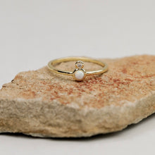 Load image into Gallery viewer, 18K gold-plated brass ring with white opal and white cubic zirconia accent displayed on a natural stone surface.