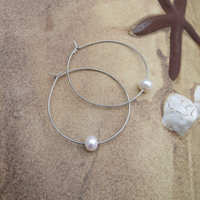 Load image into Gallery viewer, Silver hoop earrings with pearls on a sandy beach surface