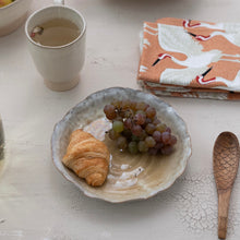 Load image into Gallery viewer, Beige ceramic bowl with a croissant and grapes on a light surface with a cup and napkin and wooden spoon.