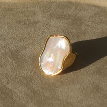 Load image into Gallery viewer, Gold-plated ring featuring an organic-shaped Mother-of-Pearl face, displayed on a soft textured tan surface with a warm shadow.