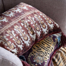 Load image into Gallery viewer, Ikat Print Lumbar Pillow and Tiger Lumbar Pillow, burgundy and cream ikat print lumbar pillow with burgundy tassels layered above plum lumbar pillow with orange tiger motif with teal geometric accents on a neutral upholstered surface. 