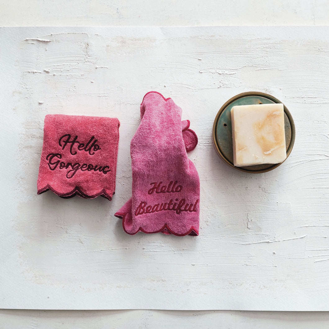 Two pink face towels with text embroidered on them, one with 