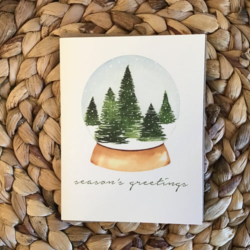 holiday card, snowball with trees and snow inside and green writing 